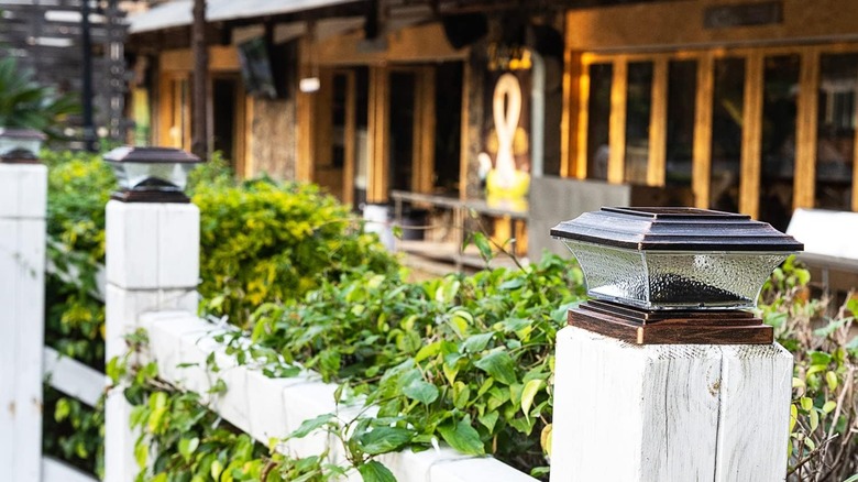 Lighted fence post caps are shown on a fence in front of a lodge