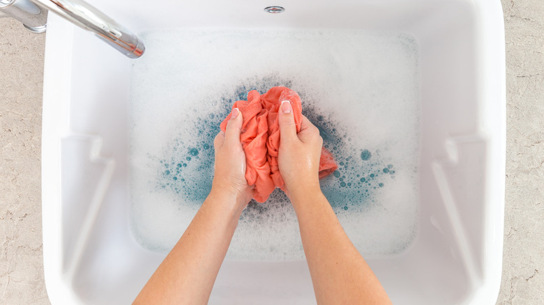 hand washing clothes in sink