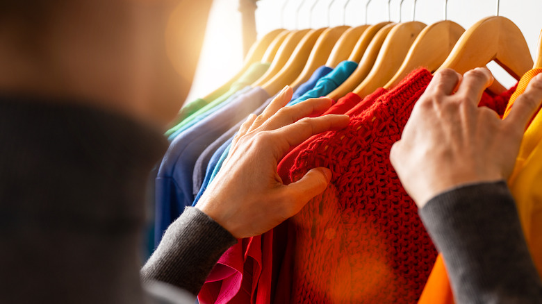 Hands sorting through clothing rack