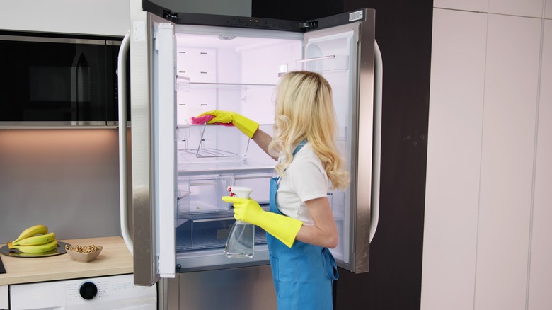Woman cleaning fridge interior
