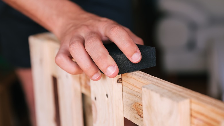 Person sanding a wood pallet