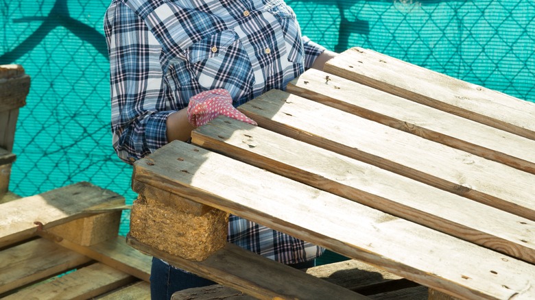 Woman picking up a wood pallet