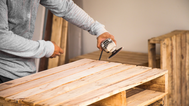 person sanding pallet 