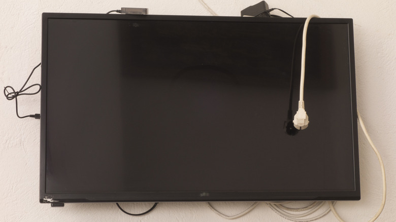 A wall-mounted TV set with messy wiring