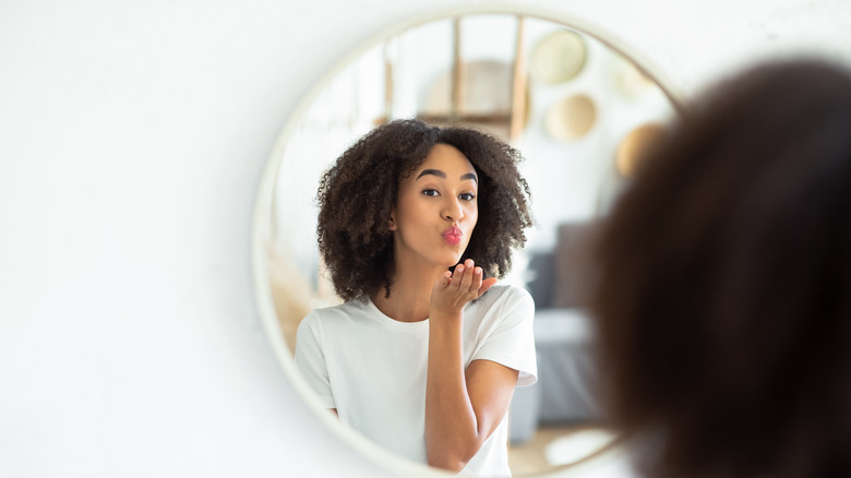 Girl blowing kiss into round mirror