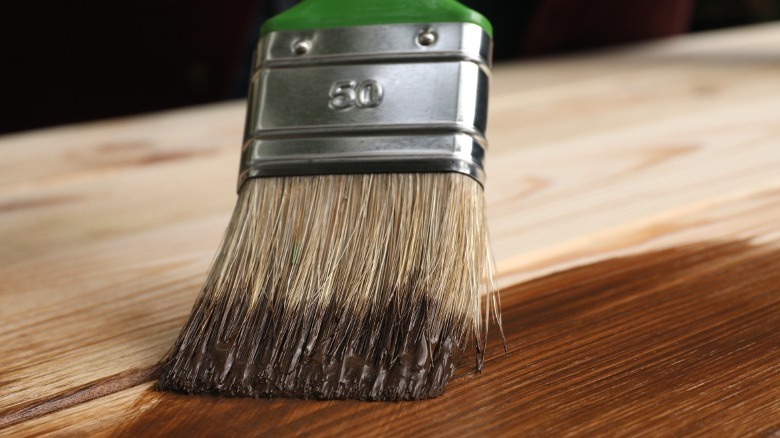 brush applying dark stain to wood board