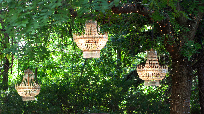 chandeliers hanging among green trees