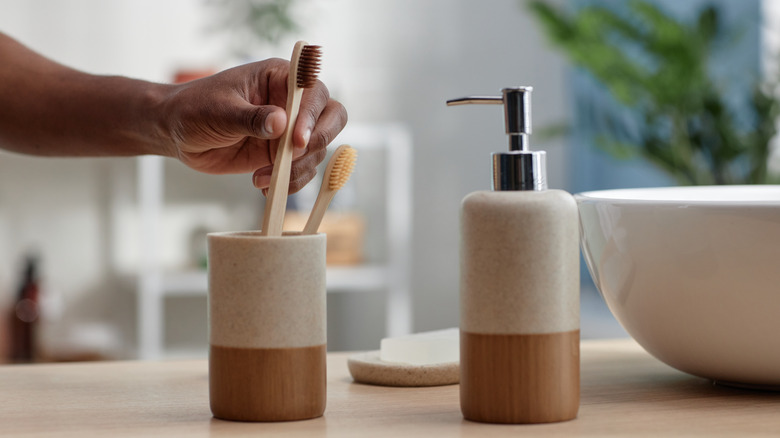 person grabbing toothbrush from two-tone toothbrush holder