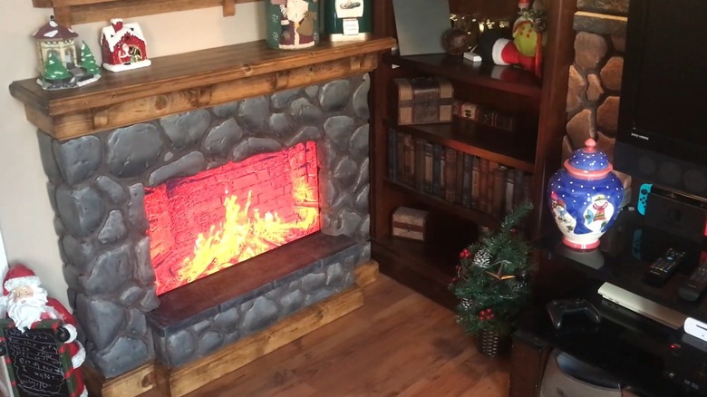 Room with a fake stone fireplace made using wood, styrofoam, and an old TV