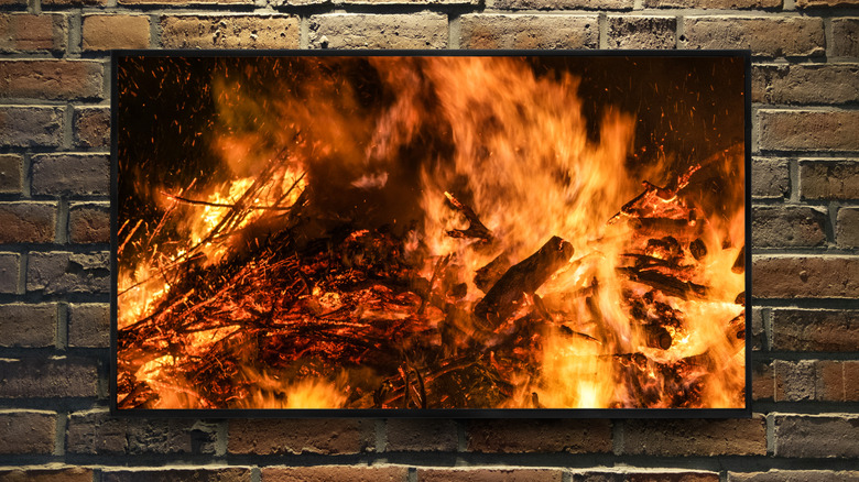 A television mounted on a brick background showing a fireplace interior