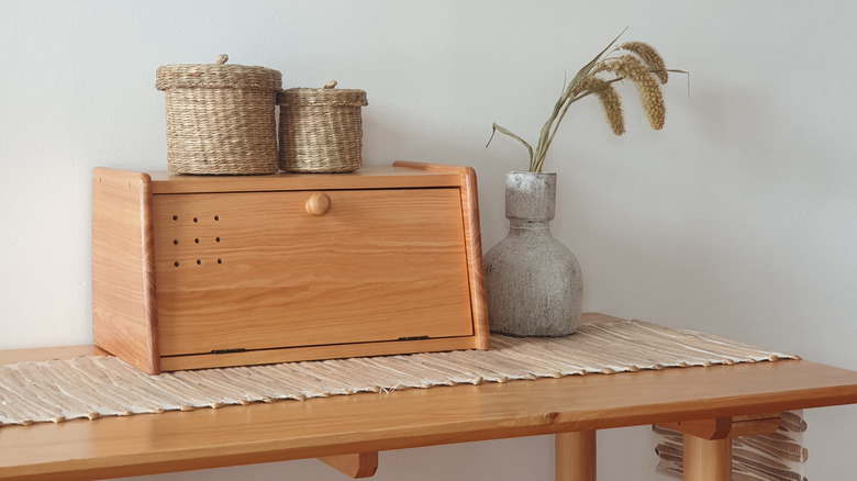 A wood breadbox with decor on a wood table