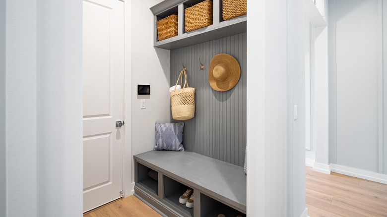 An entryway alcove with seating, baskets, and accessories.