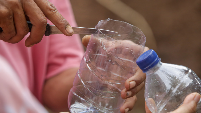 man cutting plastic bottle