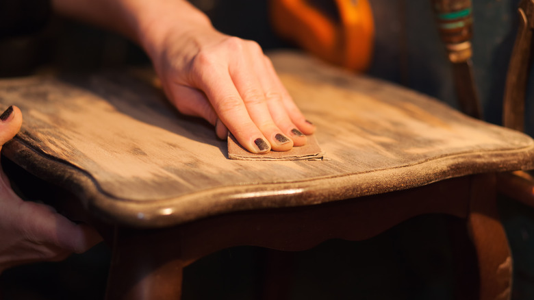 person sanding wooden table