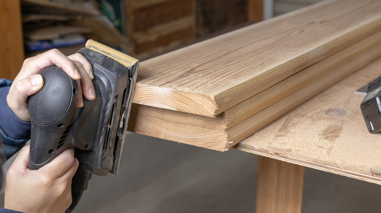 A carpenter sands a cedar board