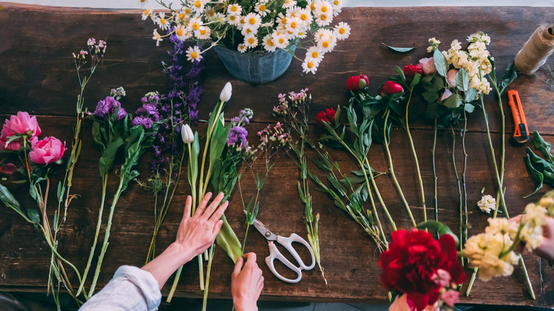 A table full of beautiful flowers being made into bouquets.