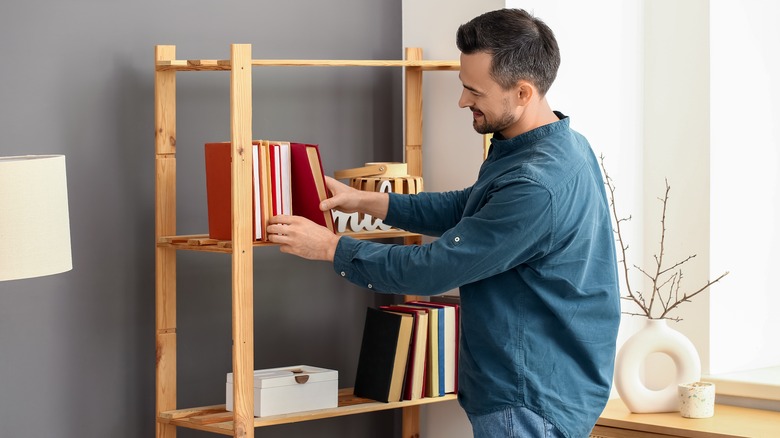 man organizing books on bookshelf