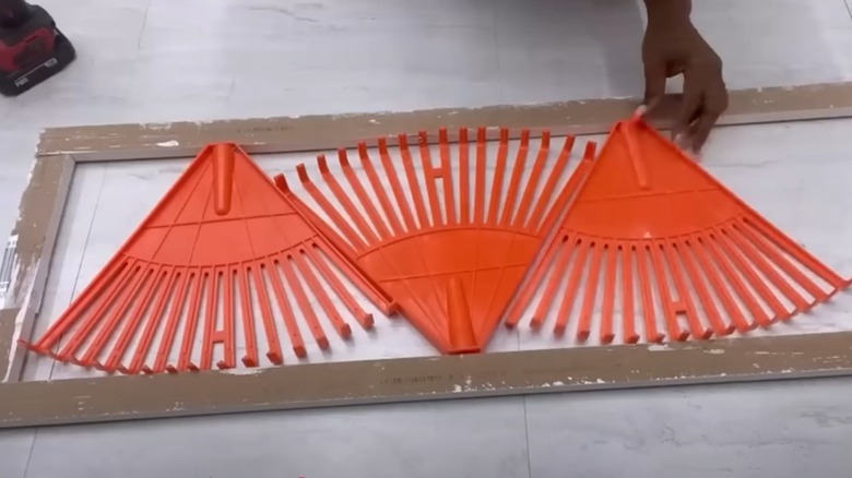 Orange rakes screwed into wooden frame