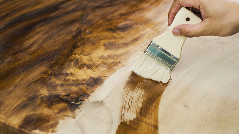 Brush painting stain onto wood surface