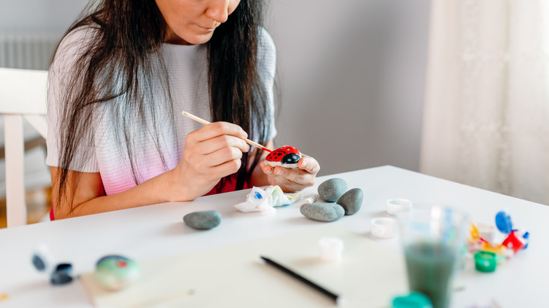 Woman painting ladybug-shaped rock