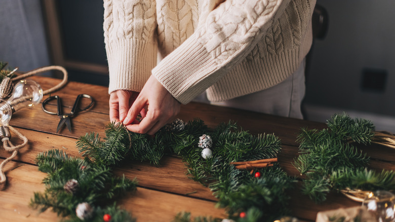 woman making Christmas wreaths on wood table