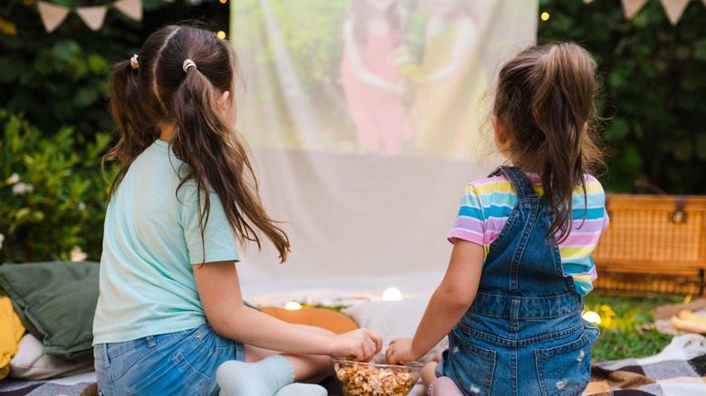 two girls sharing popcorn outdoors