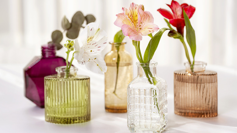 Colored glass perfume bottles holding flowers