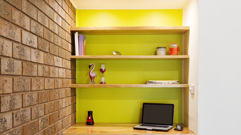 Wall recess painted yellow with shelves and desk