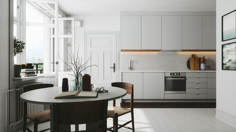 Simple white kitchen with dark table and chairs in foreground