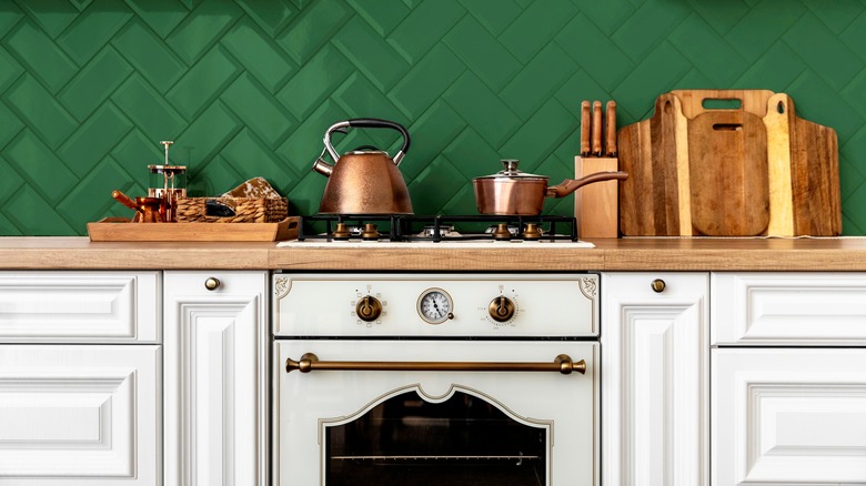 White kitchen cabinets, white range, and green tiled backsplash