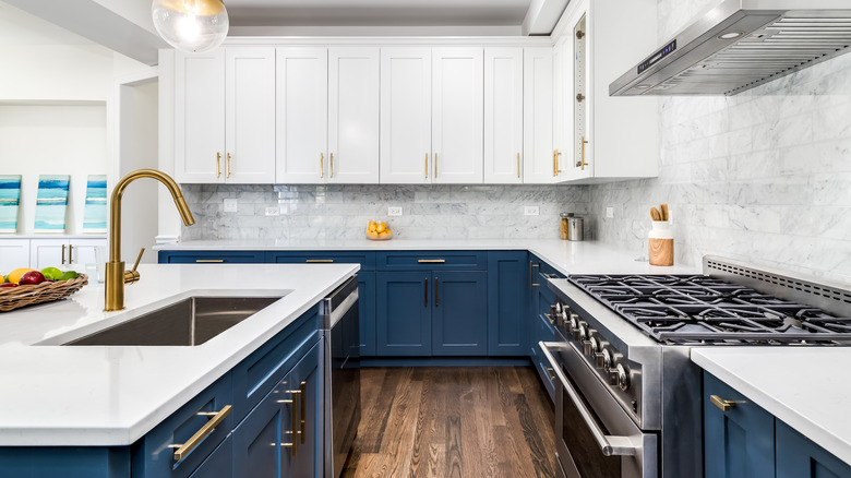 Kitchen with white uppers, blue lower cabinets, and gold hardware