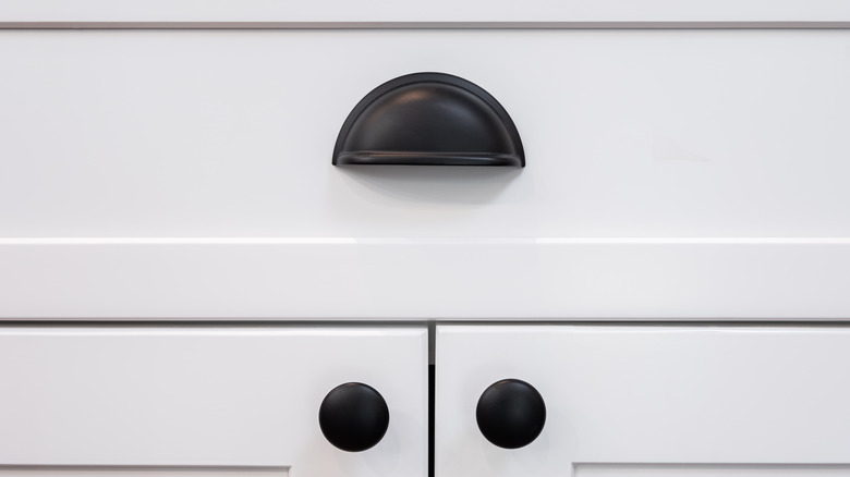 White cabinet doors and drawer front with black cup pull and knobs