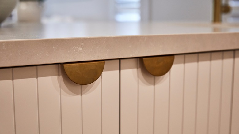 Brass half-moon edge pulls on pink-toned cabinet doors