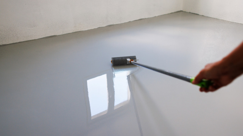 Man applying epoxy coting to a concrete garage floor