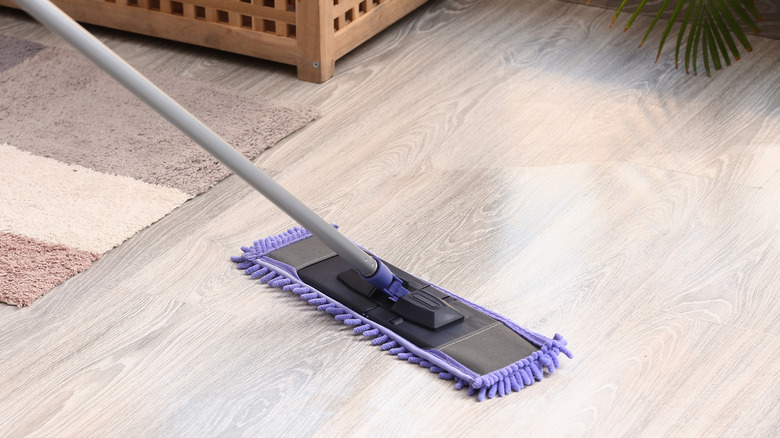 Person mopping light laminate floors with a purple mop