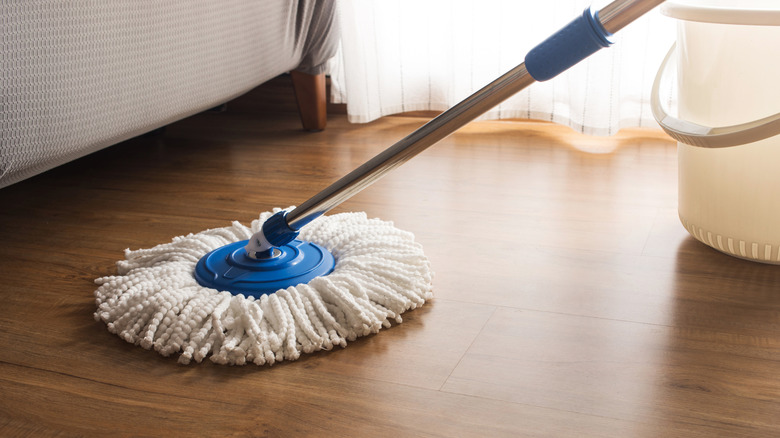 Person mopping hardwood floors with a white mop