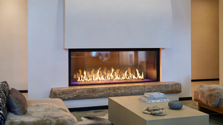 Modern gas fireplace in rustic living room with animal hide blankets