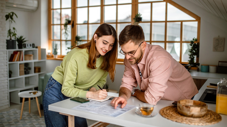 Smiling young couple going over plans in modern home