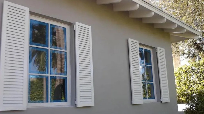 White colonial hurricane shutters on beige gray house