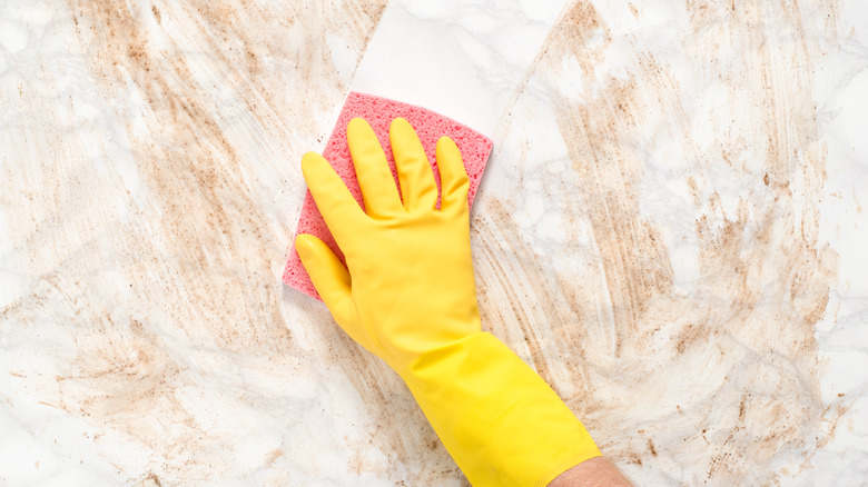 Hand with sponge wiping marble