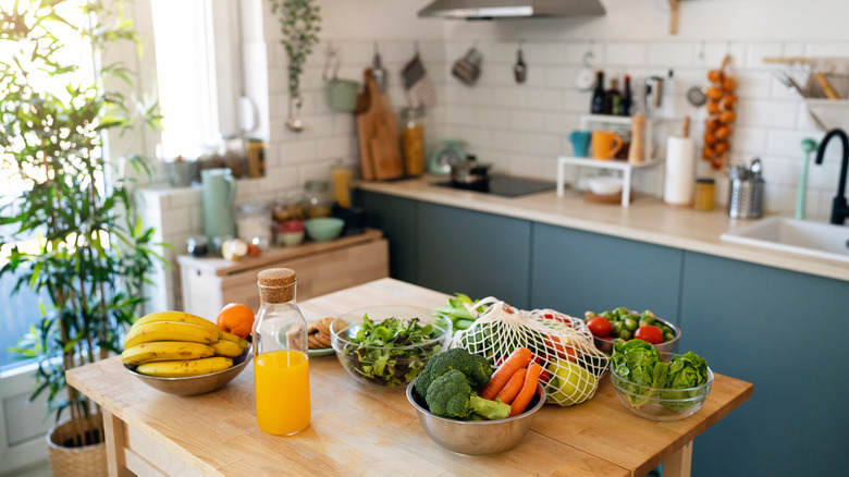 Fruits and vegetables in bowl on a wood island in a kitchen