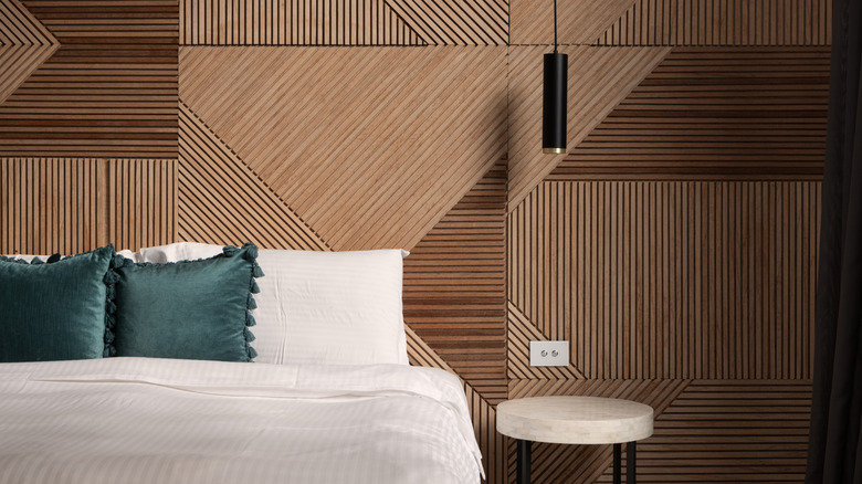 This bedroom has a slatted wood accent wall in a geometric design and natural stain.