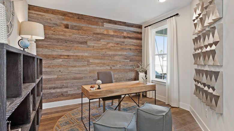 A home office wall is covered with multicolored wooden boards.