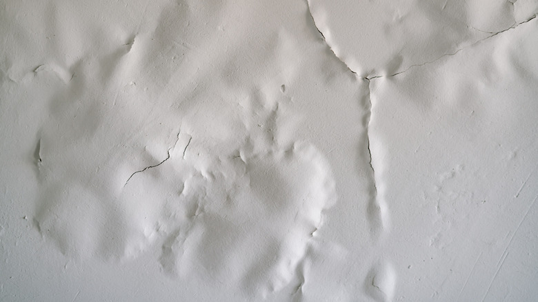 A white painted ceiling with cracks due to humidity