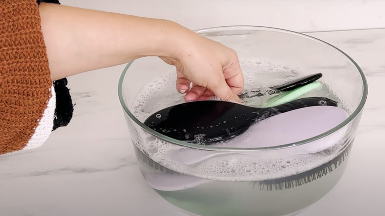 woman washing hairbrushes in bowl