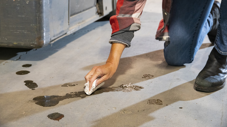 man cleaning oil stain off concrete garage floor