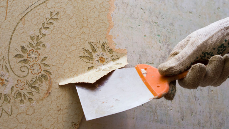 man scraping floral wallpaper