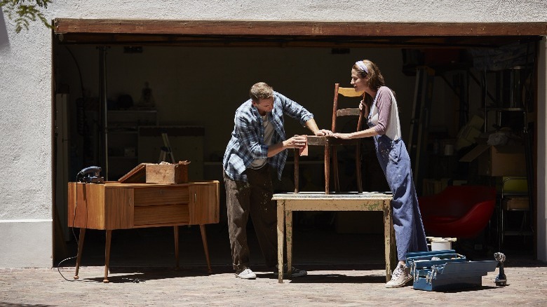 Couple cleaning furniture in front of garage