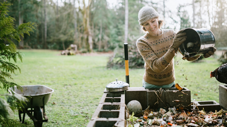 Woman dumps bucket into compost pile