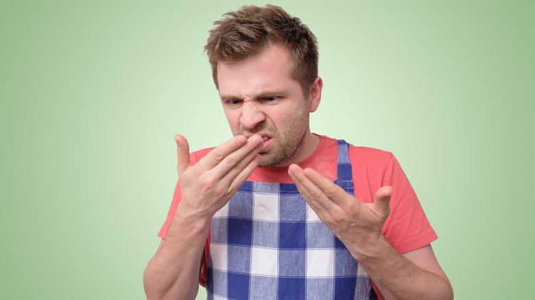 man wearing an apron smelling hands